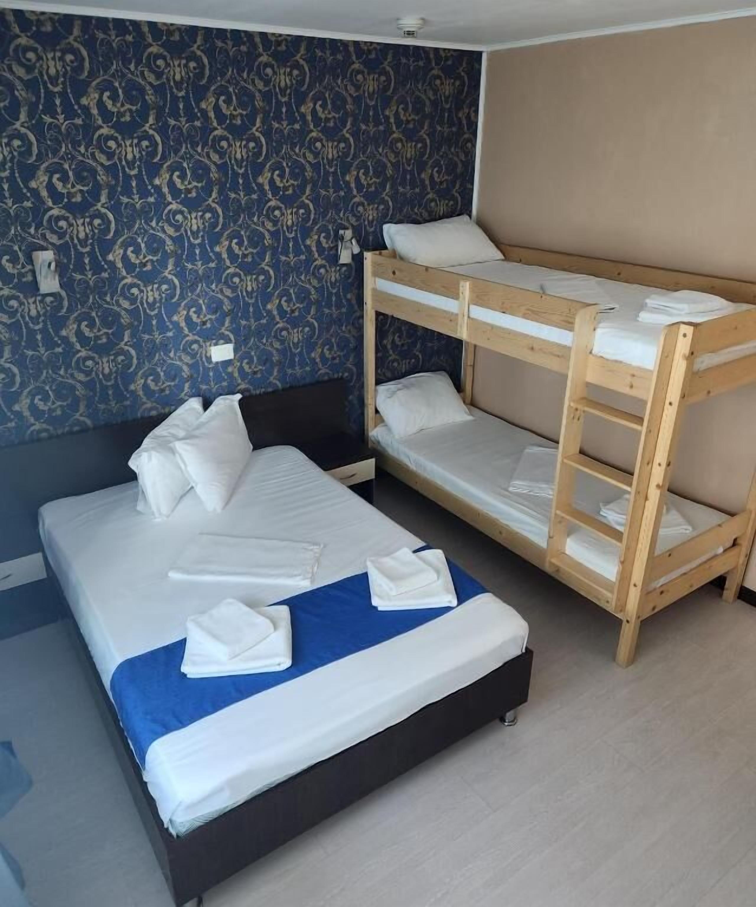 Una habitación con una cama individual y una litera, ambas con ropa blanca y toallas.