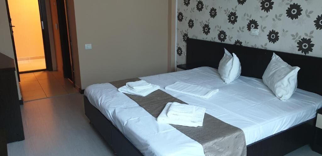 Una cama bien hecha con sábanas y almohadas blancas, un cabecero de madera y un estampado floral en la pared.
