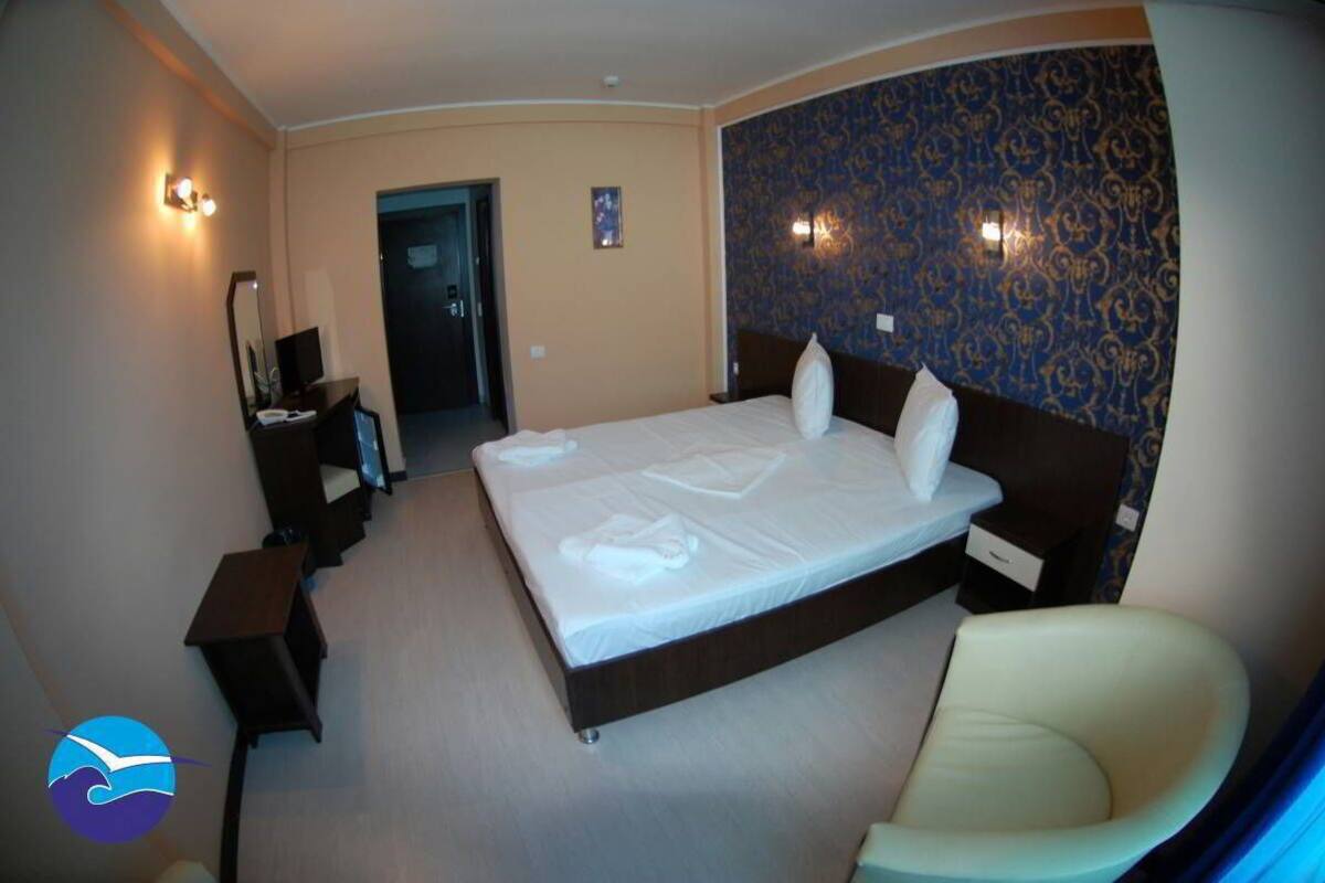 A hotel room with a large bed, bedside tables, a chair, and a mirror.