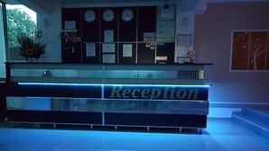 A reception area with a blue-lit reception desk, clocks, and a Visa sign. - Vila Alessia (Eforie)