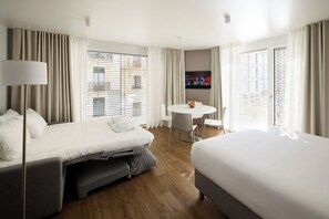 A hotel room with a bed, a desk, and a TV.