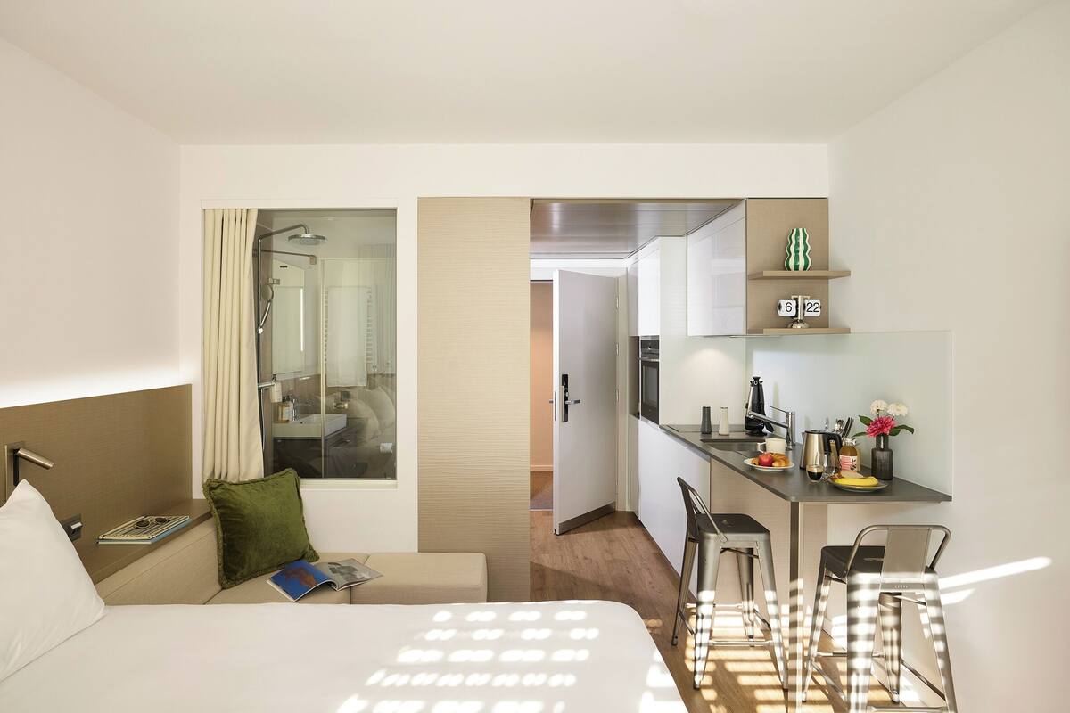 Une chambre d’hôtel comprenant un lit, un petit coin salon, une kitchenette et une salle de bain.