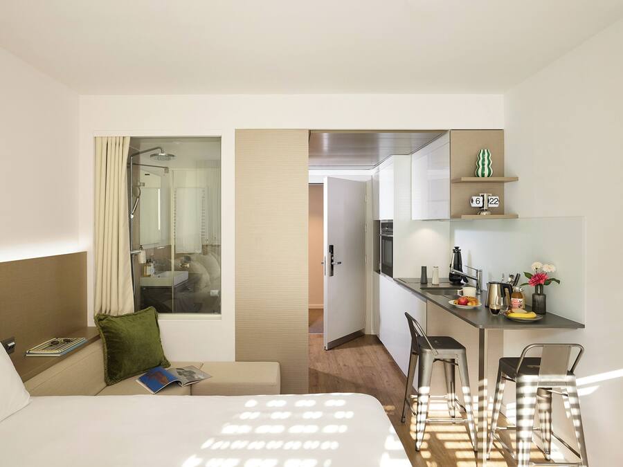 Ein Hotelzimmer mit Bett, Leseecke, Bad und Küchenzeile.