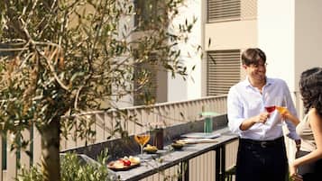 A balcony with a dining setup including plates, glasses, and a bottle.