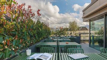 Un espace extérieur aménagé avec des tables et des chaises vertes, un magazine et un ordinateur portable.
