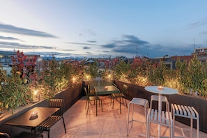 Relax in a rooftop seating area surrounded by lush greenery and city views.