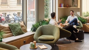 A modern interior with a green armchair, a round table with candles, and a view of the street outside. - Base Geneva (Geneva)
