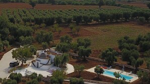 Un olivier avec un bâtiment blanc doté d’une piscine et d’un espace extérieur aménagé pour s’asseoir.
