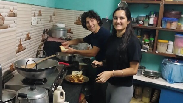 Une cuisine équipée d’une cuisinière, de casseroles et d’une personne qui prépare des aliments.