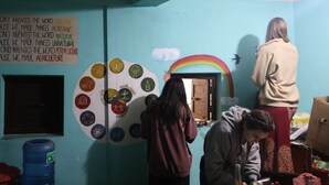 Une pièce dont un mur est décoré d’icônes circulaires et d’une fresque représentant un arc-en-ciel, et qui contient également un distributeur d’eau et une porte.