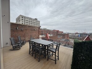 Una terraza en la azotea con una mesa y sillas, un muro de ladrillo y vistas de la ciudad.
