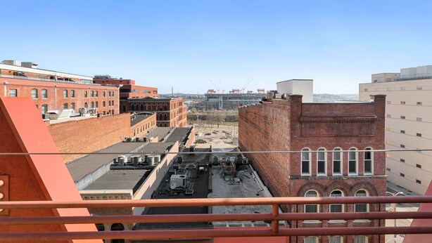Une vue sur un paysage urbain, avec un mélange de bâtiments anciens en briques et de constructions modernes, dont un grand bâtiment rouge au premier plan et un chantier de construction Nissan à l’arrière-plan.