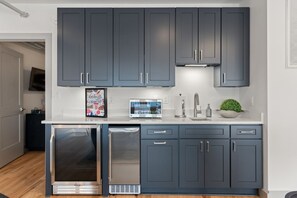 Une cuisine moderne avec des meubles de couleur gris foncé, des appareils en acier inoxydable et un plan de travail blanc.