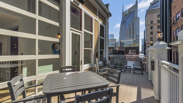 An outdoor patio with tables and chairs, large windows, and a view of a tall building in the background.