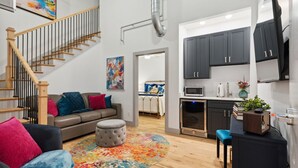 A modern apartment with a living room, kitchen, and staircase.