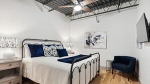 A bedroom with a bed, bedside tables, a chair, and a ceiling fan.