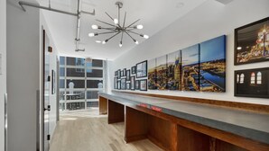 Un moderno vestíbulo de hotel con un mostrador de recepción alargado, obras de arte con vistas a la ciudad y una vista del exterior del edificio.