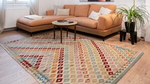 A living room with a sectional sofa, a coffee table, a patterned rug, a floor lamp, and a large painting on the wall. - 2BR Greek Home | Private Backyard 20' to Acropolis (Athens)