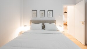 A bedroom with a bed, white bedding, a headboard, and three framed pictures on the wall. - 2BR Greek Home | Private Backyard 20' to Acropolis (Athens)
