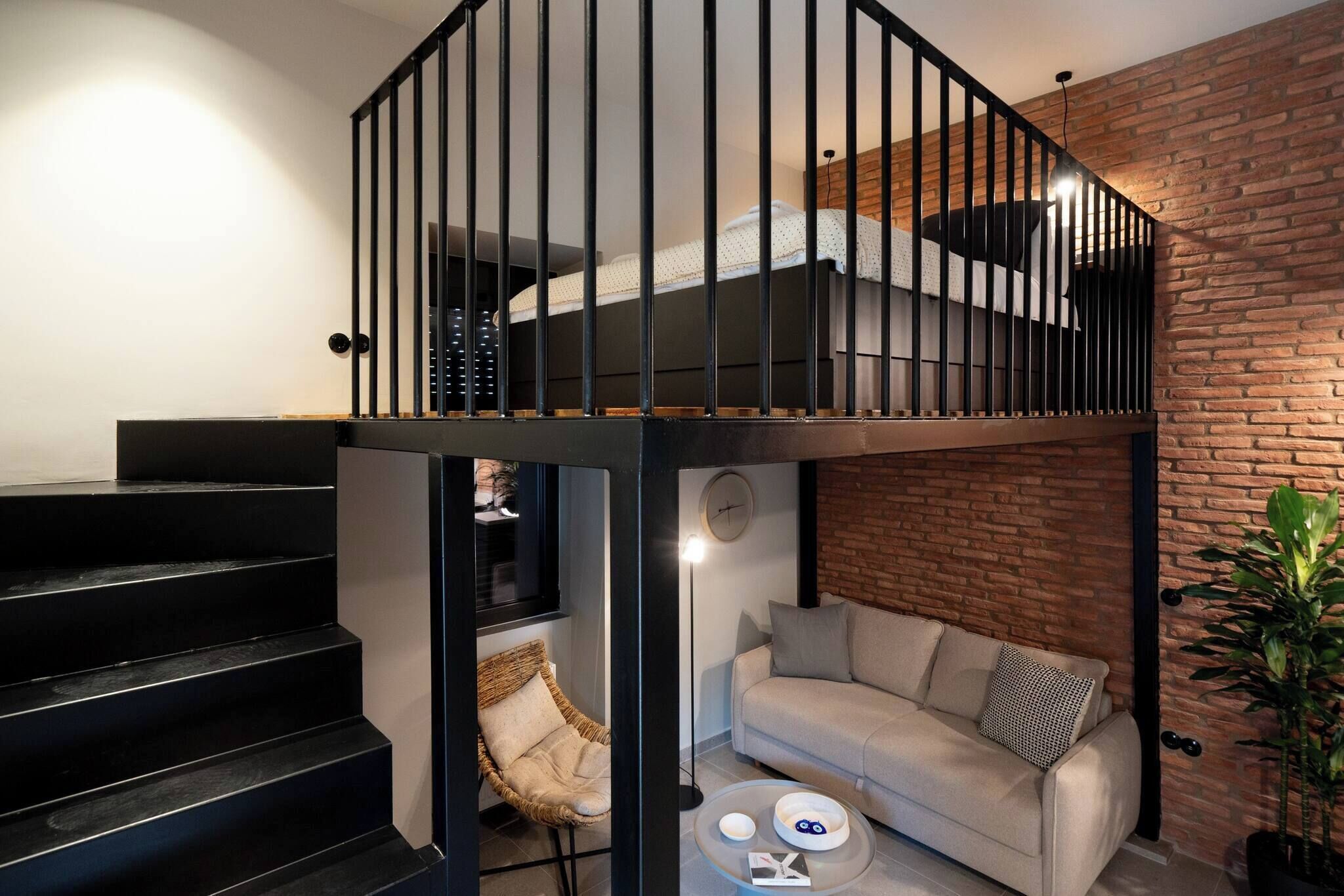 A loft-style bedroom with a bunk bed, a staircase, a sofa, and a coffee table.