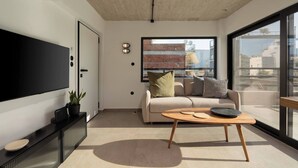 Un salon moderne doté d’un téléviseur à écran plat, d’un canapé, d’une table basse et d’une grande fenêtre offrant une vue sur la ville.