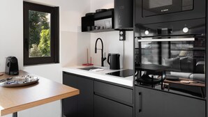 Une cuisine moderne avec des appareils électroménagers noirs, une fenêtre et une vue sur la verdure.
