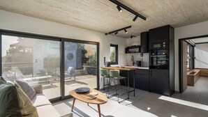 Une cuisine moderne avec des appareils électroménagers noirs, un coin repas doté d’une table en bois et une grande porte-fenêtre coulissante donnant sur une terrasse extérieure.