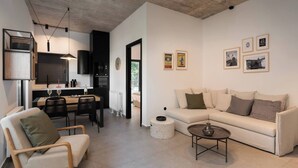 A modern living room with a sofa, a coffee table, and a dining area with chairs and a table. - 2BR Suite Apt • Acropolis Rooftop Views • By Metro (Athens)