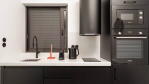 A modern kitchen with a Bosch oven, a coffee maker, and a kettle on the counter. - 2BR Suite Apt • Acropolis Rooftop Views • By Metro (Athens)