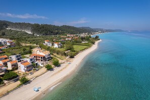 Uma área costeira com praia, águas azuis cristalinas e uma combinação de edifícios residenciais.