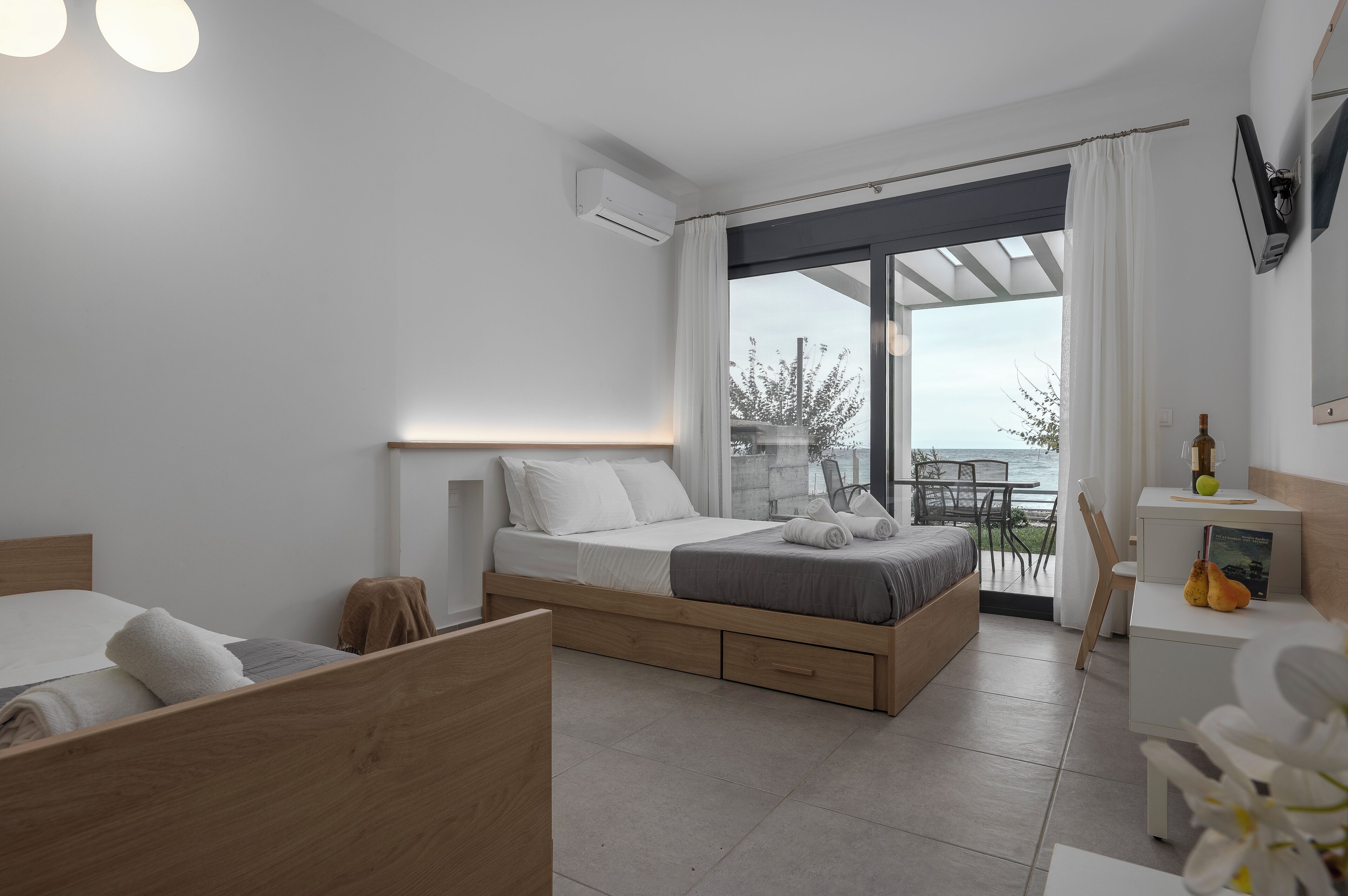 A modern bedroom with a bed, bedside table, and a view of the outdoors.