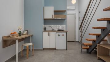 Een moderne keuken met een geïntegreerde koelkast, houten kasten en een kleine eethoek met een kruk.