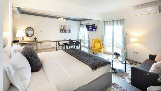 A hotel room with a bed, a desk, a chair, a TV, and a window with curtains.