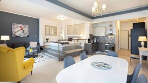 A modern hotel room with a dining area, a kitchen, and a living space.