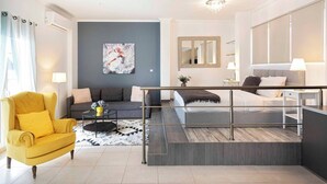 A modern living room with a sofa, a yellow armchair, a coffee table, and a staircase leading to a bedroom.