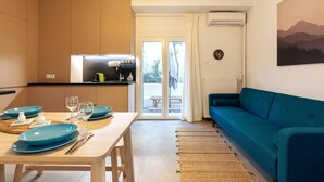 A modern kitchen with a dining area, a sofa, and a view of the outdoors.