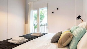 A neatly made bed with folded towels, a black throw blanket, and patterned pillows.