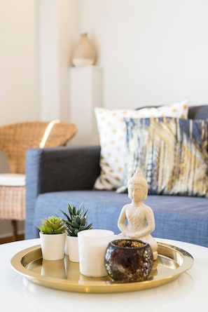 Ein Tablett mit einer Buddha-Statue, einer kleinen Pflanze und einer Kerze auf einer weißen Tischplatte.