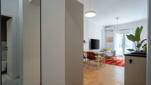 A modern living room with a dining area, a TV, and a large window. - Urban Escape: Exarcheia Remodel (Athens)