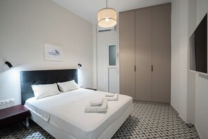 Une chambre d’hôtel bien aménagée, avec un grand lit, une table de chevet, une armoire et un luminaire suspendu.