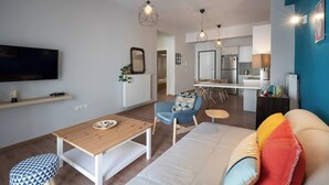 A modern living room with a TV, wooden table, blue armchair, and colorful cushions. - Exclusive Apt In The  Of Athens'_2BD+2 Bathrooms (Athens)