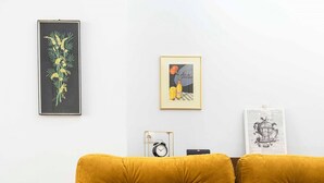 A mustard-colored sofa, a glass coffee table, and framed artwork on a white wall. - Athens' Best Location~ Unique Magnificent Studio (Athens)