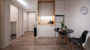 A modern kitchen with white cabinets, a wooden countertop, and a black chair at a round table. - 1BR In Plaka | Rooftop Access w/ Acropolis View (Athens)