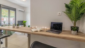 Un espacio de oficina moderno con un escritorio de madera, una computadora portátil, un libro abierto y plantas en macetas.