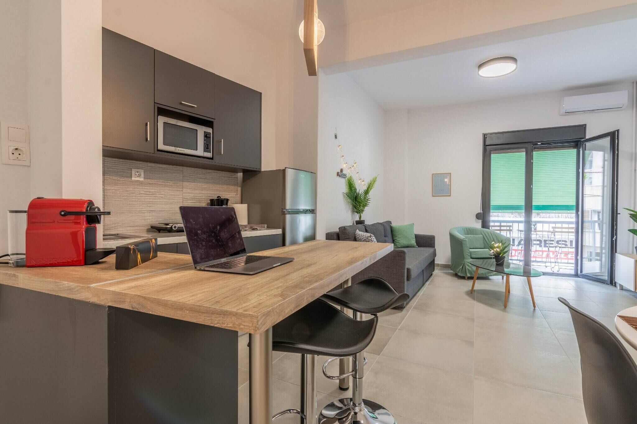Una cocina moderna con una isla de madera, taburetes de bar y una cafetera roja.
