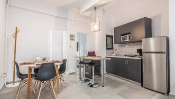 Una cocina moderna con armarios oscuros, un refrigerador de acero inoxidable y una zona de comedor con mesa y sillas.