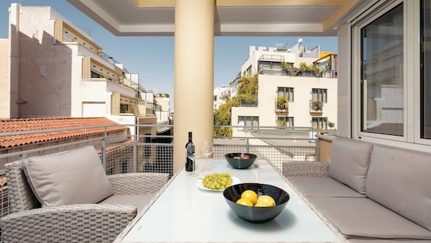 A balcony with wicker furniture, a glass table, and bowls of fruit. - Prime central location Athens, Big Balcony (Athens)