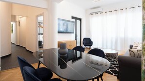 A modern living room with a glass-top dining table, black chairs, a sofa, a TV, and a large window with curtains. - Prime central location Athens, Big Balcony (Athens)