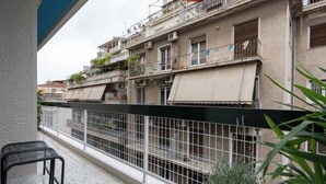 A balcony with a metal railing, a black chair, and a potted plant.