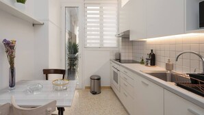 A modern kitchen with white cabinetry, a stainless steel sink, and a dining area with a table and chairs.
